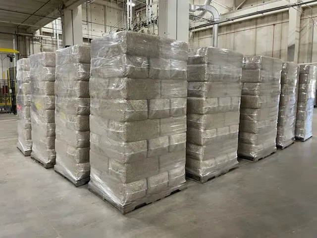 Shrink-wrapped pallets of hemp hurd bales stacked in a warehouse